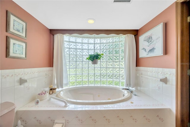 bathroom featuring a relaxing tiled tub and toilet