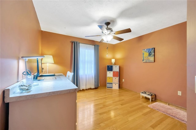 home office featuring ceiling fan, a textured ceiling, and light wood-type flooring