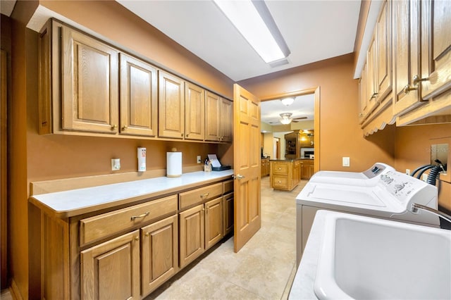 laundry room featuring sink, washer and clothes dryer, cabinets, and ceiling fan