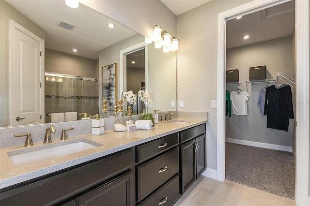 bathroom with a shower with shower door, tile patterned floors, and vanity