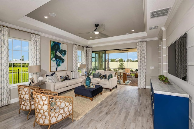 living room featuring crown molding, hardwood / wood-style floors, and a tray ceiling