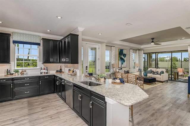 kitchen with dishwasher, a raised ceiling, kitchen peninsula, sink, and light hardwood / wood-style flooring