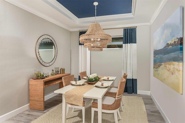 dining room featuring a raised ceiling, ornamental molding, a chandelier, and hardwood / wood-style flooring