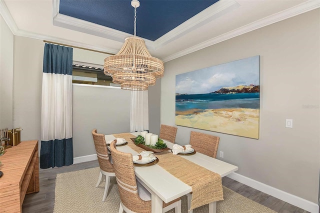 dining area with an inviting chandelier, wood-type flooring, a raised ceiling, and crown molding