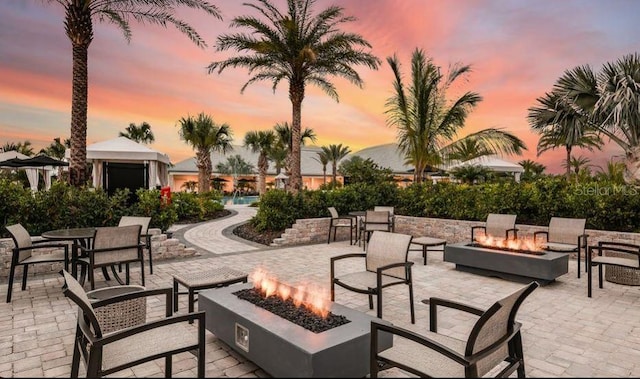 patio terrace at dusk featuring a gazebo and a fire pit