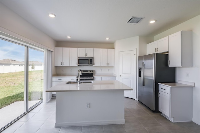 kitchen featuring sink, white cabinetry, appliances with stainless steel finishes, and a center island with sink