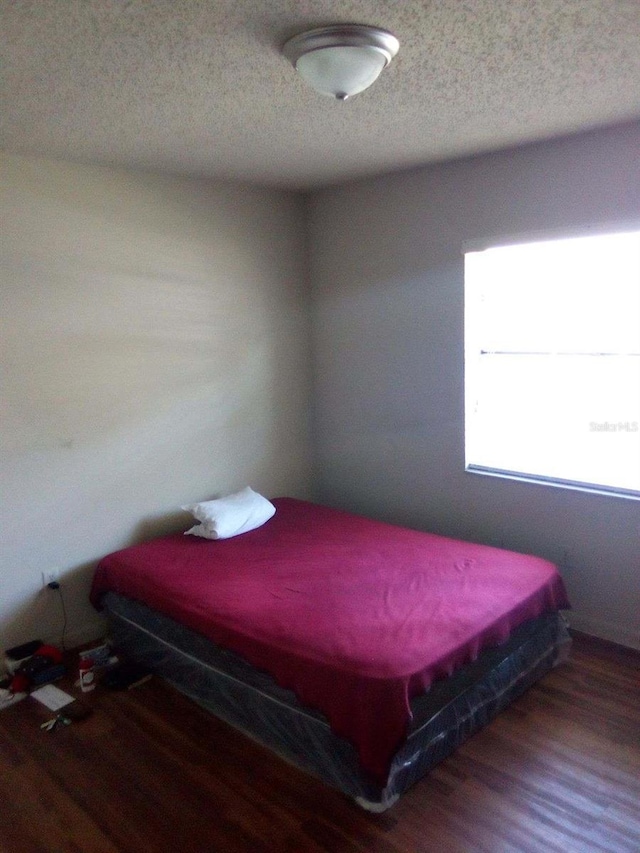 bedroom featuring a textured ceiling and wood finished floors