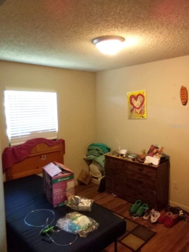 bedroom with a textured ceiling and wood finished floors