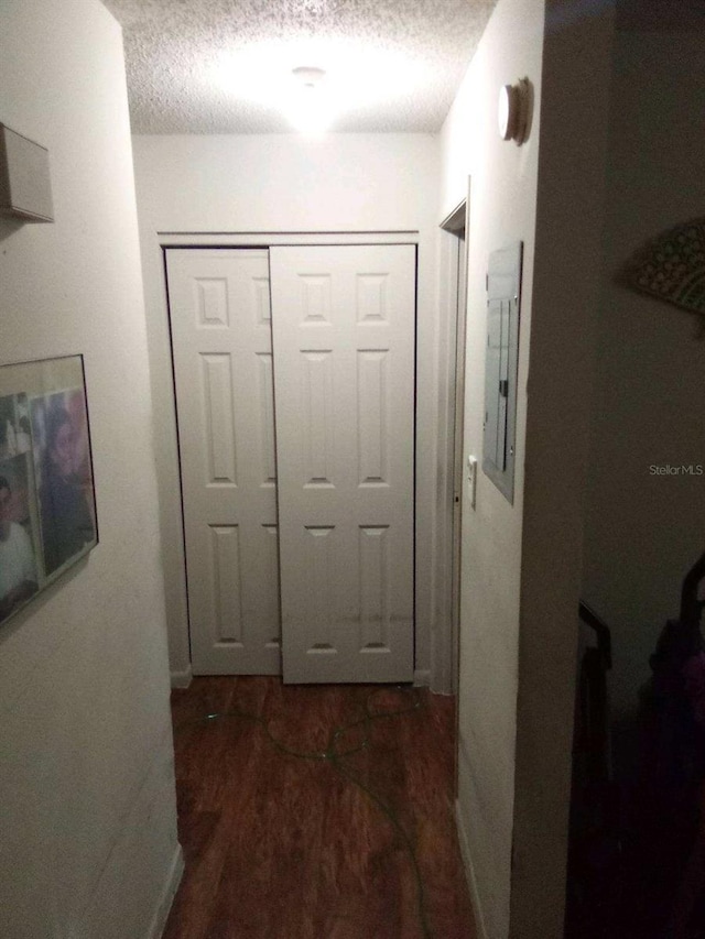 hallway featuring dark wood-style flooring, electric panel, and a textured ceiling