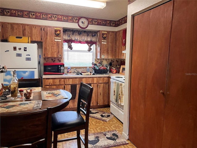 kitchen with white appliances, brown cabinets, light countertops, light floors, and a sink