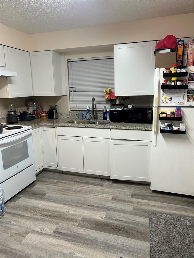 kitchen with white appliances, white cabinetry, and a sink