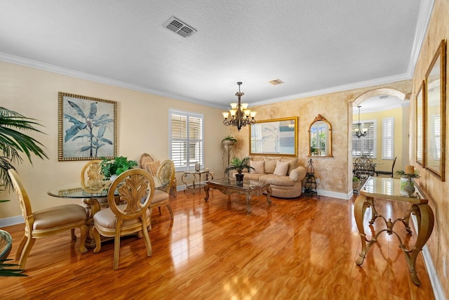 living room featuring a textured ceiling, crown molding, hardwood / wood-style floors, and a chandelier