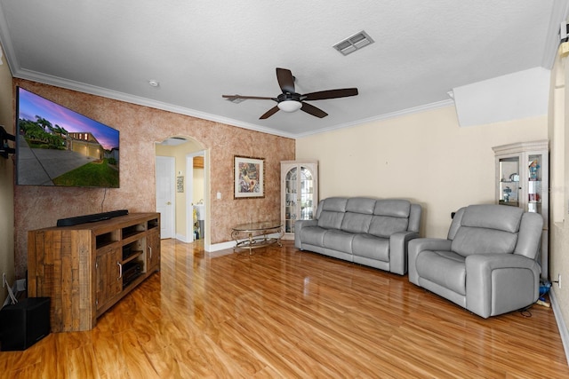 living room featuring ceiling fan, a textured ceiling, light wood-type flooring, and crown molding