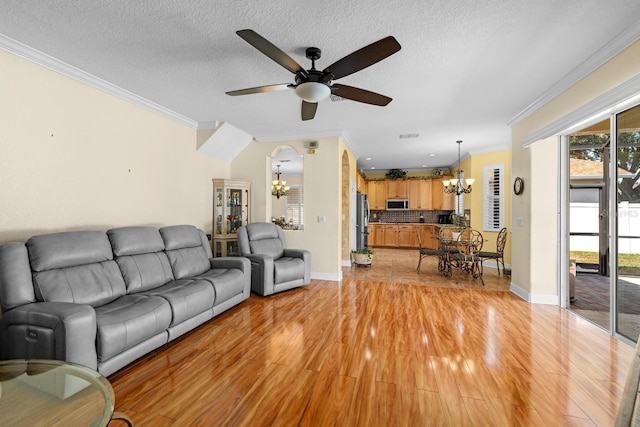 living room featuring a textured ceiling, ceiling fan with notable chandelier, crown molding, and light hardwood / wood-style flooring