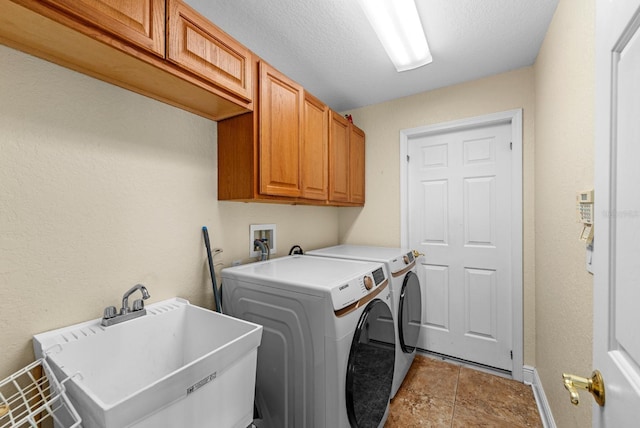 laundry room with independent washer and dryer, a textured ceiling, tile patterned flooring, cabinets, and sink