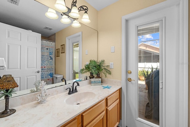 bathroom featuring vanity, toilet, a shower with shower curtain, and a notable chandelier