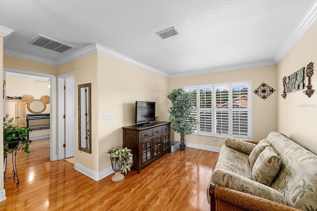 living room featuring ceiling fan, a textured ceiling, light wood-type flooring, and ornamental molding