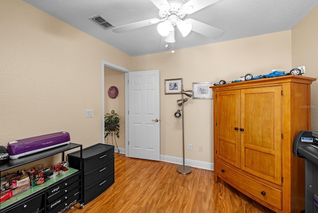 misc room with a textured ceiling, light hardwood / wood-style floors, and ceiling fan