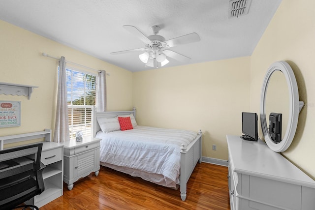 bedroom with a textured ceiling, hardwood / wood-style floors, and ceiling fan