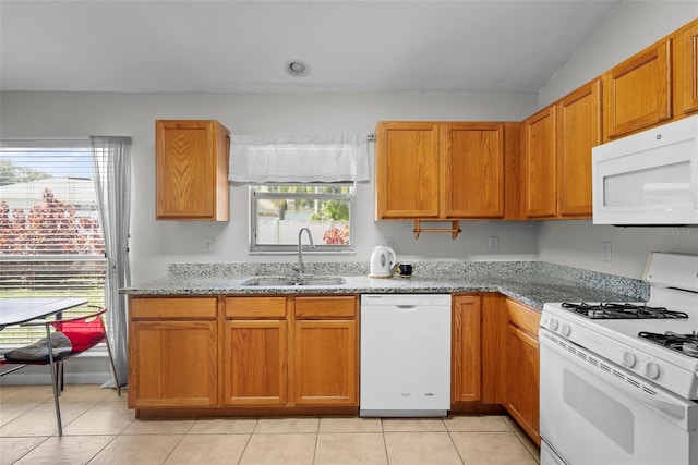 kitchen with light tile patterned flooring, sink, white appliances, stone counters, and vaulted ceiling