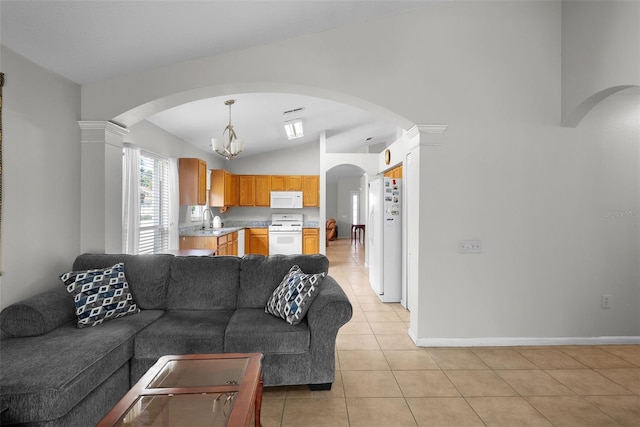 living room featuring light tile patterned floors, ornate columns, lofted ceiling, sink, and a notable chandelier