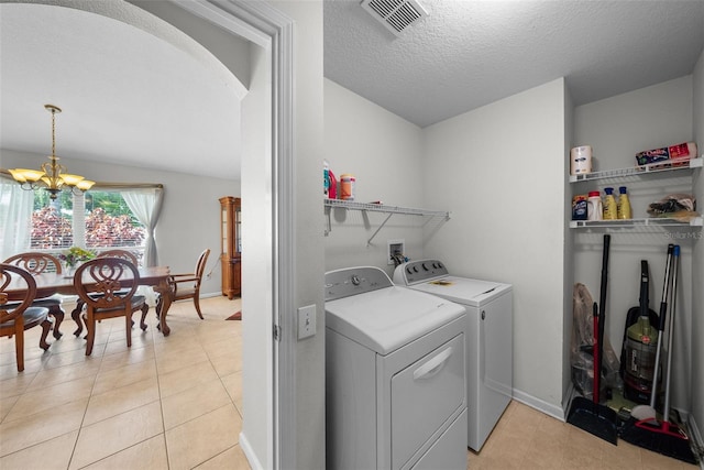 washroom featuring washer and clothes dryer, an inviting chandelier, light tile patterned floors, and a textured ceiling