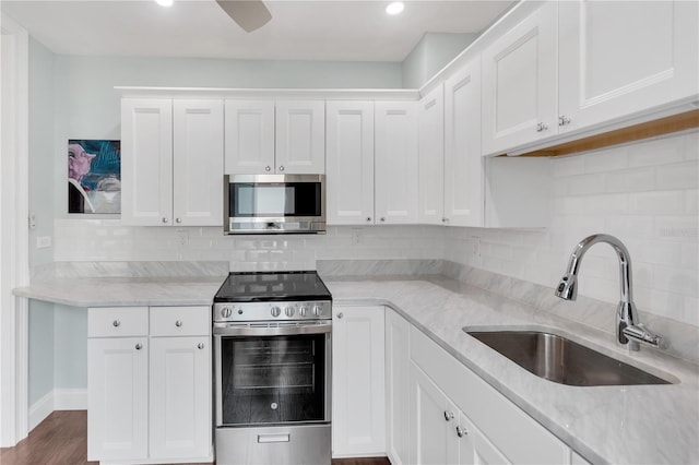 kitchen featuring sink, backsplash, white cabinetry, light stone counters, and stainless steel appliances