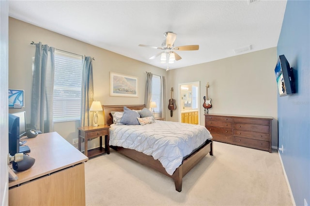 bedroom featuring ceiling fan, light colored carpet, and ensuite bath