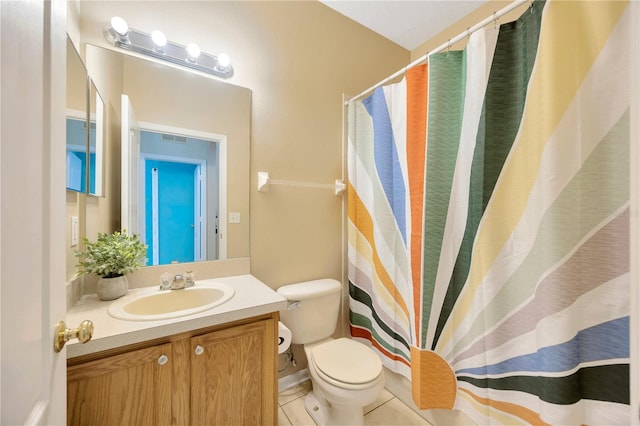 bathroom with toilet, vanity, and tile patterned floors