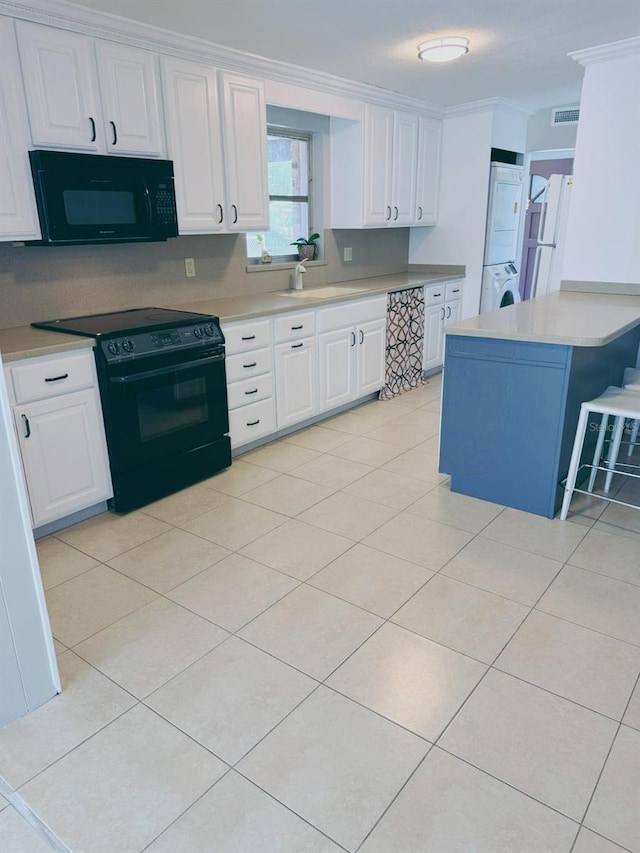 kitchen featuring white cabinets, ornamental molding, black appliances, sink, and stacked washer and clothes dryer