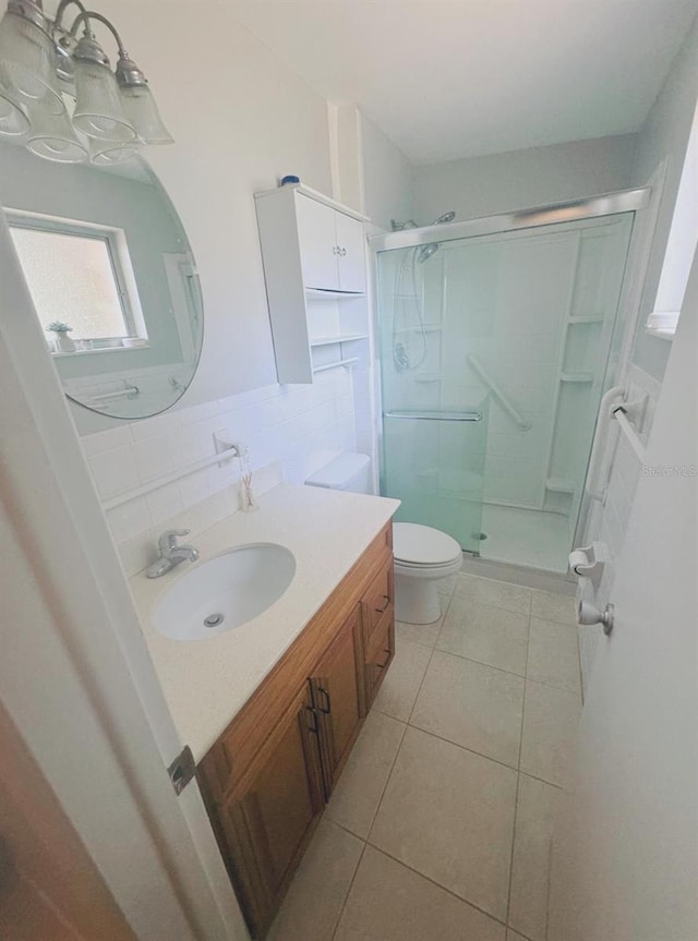 bathroom with a shower with door, toilet, tile patterned floors, tile walls, and vanity