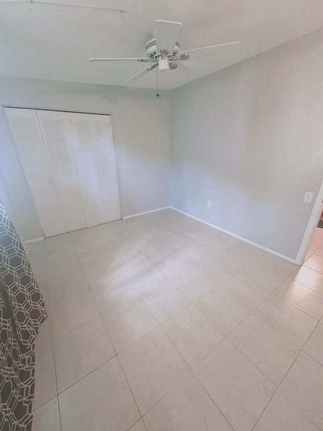 unfurnished bedroom with light tile patterned flooring, a closet, and ceiling fan