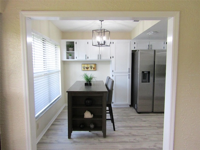 kitchen featuring a notable chandelier, pendant lighting, light hardwood / wood-style flooring, stainless steel fridge with ice dispenser, and white cabinets