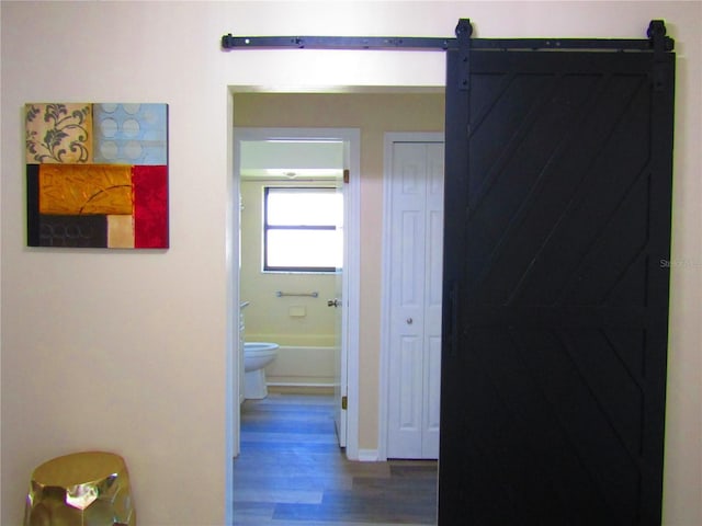 corridor with hardwood / wood-style floors and a barn door