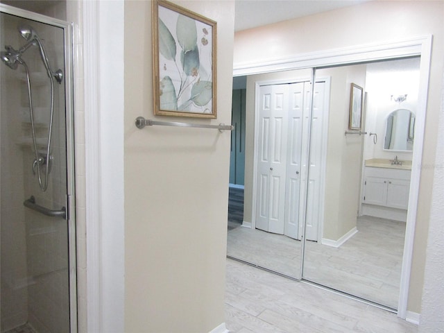 2501 Lonigan Pl, Sun City Center, FL 33573 - bathroom featuring baseboards, wood finished floors, vanity, and a stall shower
