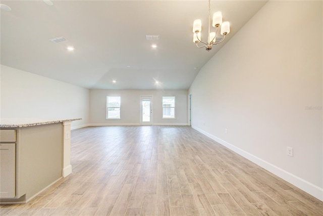 unfurnished living room featuring a chandelier and light wood-type flooring