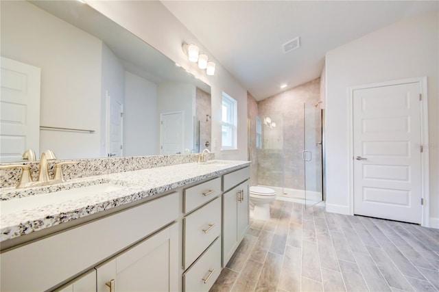 bathroom featuring lofted ceiling, vanity, toilet, and a shower with shower door