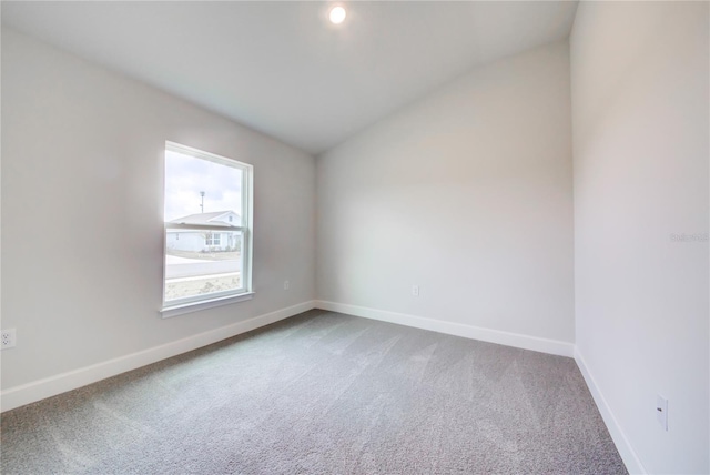 carpeted empty room with vaulted ceiling