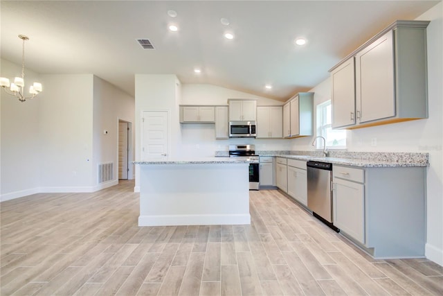 kitchen with appliances with stainless steel finishes, a center island, gray cabinetry, and pendant lighting