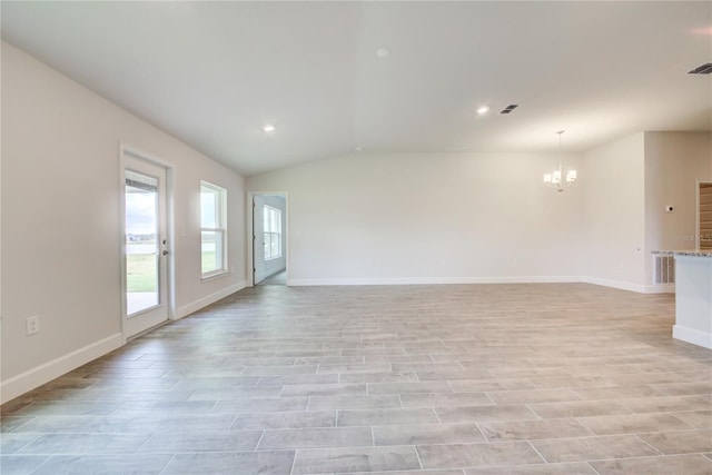 empty room featuring light hardwood / wood-style flooring, vaulted ceiling, and a chandelier