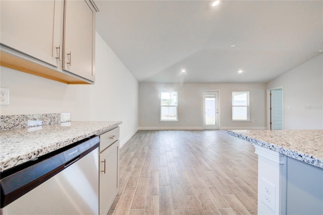 kitchen with vaulted ceiling, dishwasher, light stone countertops, and light wood-type flooring