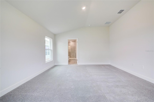 spare room featuring lofted ceiling and light colored carpet