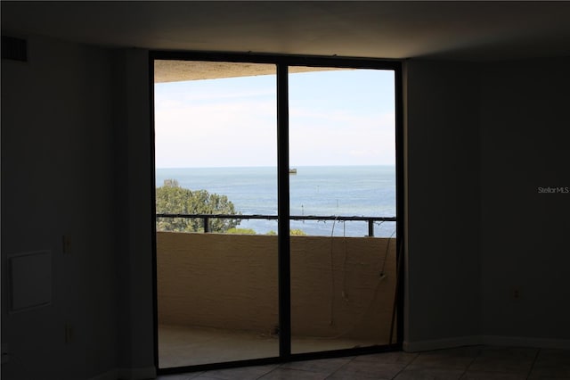 empty room with light tile patterned flooring and a water view