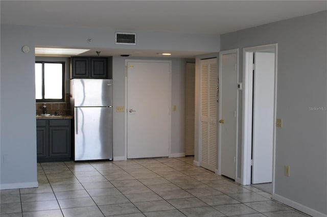 kitchen with light tile patterned flooring, decorative backsplash, sink, and stainless steel fridge