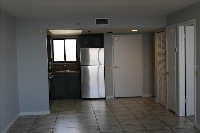 kitchen featuring gray cabinets, decorative backsplash, sink, stainless steel refrigerator, and light tile patterned floors