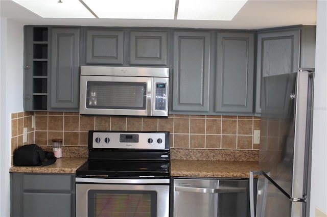 kitchen featuring decorative backsplash, stainless steel appliances, and gray cabinets