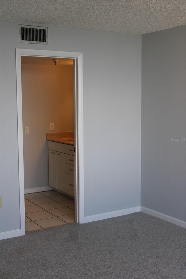 carpeted empty room with a textured ceiling