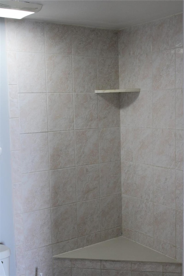 bathroom with a tile shower and toilet