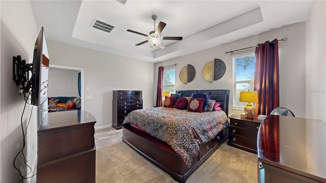 carpeted bedroom featuring a tray ceiling and ceiling fan