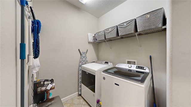 clothes washing area with light tile patterned flooring, independent washer and dryer, and a textured ceiling